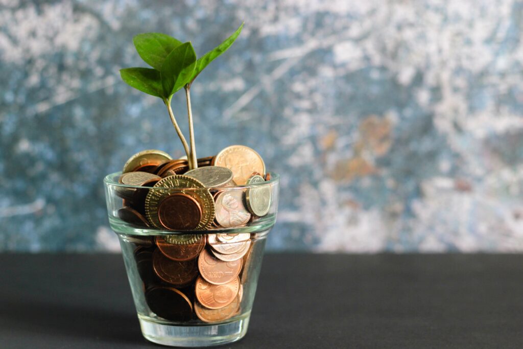 Plant growing out of coins in a glass cup